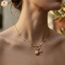 Gold necklace with a shell and star pendant on a person's neck, brand 'Zzilya' visible.