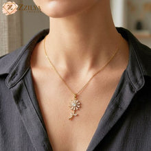 Gold necklace with a floral pendant worn by a person, brand 'Zzilya' visible.