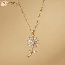 Gold necklace with a floral pendant on a beige background, featuring the brand 'ZZILYA'.