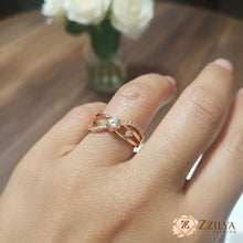 Close-up of a woman's hand wearing a Zzilya rose gold criss-cross ring with a central round diamond and pavé-set crystals on a triple-band design.