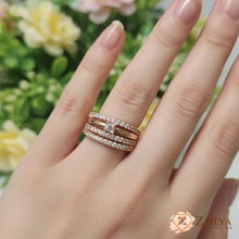 Close-up of a hand wearing a Zzilya rose gold statement ring featuring four stacked rows of pavé crystals and a central square-cut stone