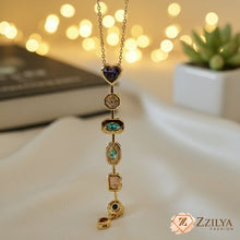 Gold necklace with gemstones on a blurred background with lights and a plant.