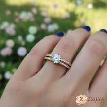 Close-up of a hand wearing a Zzilya rose gold solitaire ring with a large round-cut center stone and a double-row pavé crystal split-shank band.