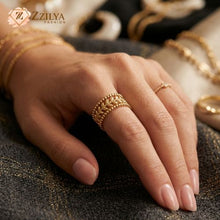 A detailed gold ring with an openwork laurel leaf pattern between two rows of small beaded metal spheres, resting inside a velvet-lined wooden jewelry box with white rose petals by ZZilya fashion