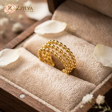 Gold beaded ring on a textured surface with 'ZZILYA' branding.