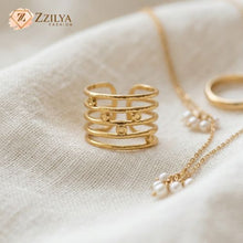 Gold ring and necklace with pearls on a beige fabric background, featuring the brand 'ZZILYA'.