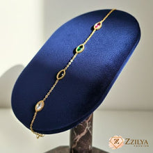 Close-up of a delicate 18k gold-plated chain bracelet adorned with oval and marquise-shaped gemstones in emerald green, ruby red, and light pink, featuring textured bezel settings by Zzilya fashion