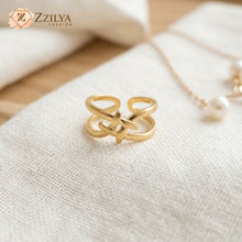 Gold ring with intricate design on a textured fabric surface, branded 'ZZILYA'.