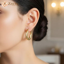Woman wearing chunky gold textured hoop earrings with a quilted embossed pattern, styled for a casual everyday look by Zzilya Fashion.