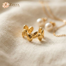 Gold jewelry set on a beige fabric background with 'ZZILYA' branding.