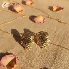 Anti Tarnish Earrings with leaf-like design by Zzilya Fashion on a beige fabric background with pink petals.