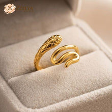 Gold snake-shaped ring on a soft surface with 'ZZILYA' branding.