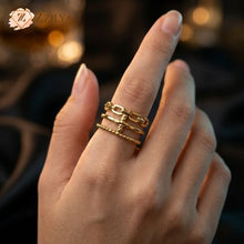 A hand wearing a ZZILYA gold-plated triple-layered ring featuring a textured link chain top band, a center band with a cross detail, and a beaded bottom band.