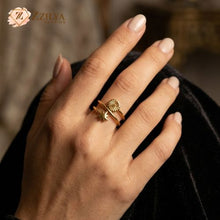 Hand wearing a gold ring with a blurred background, featuring the brand 'ZZILYA'.