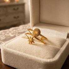 A gold-toned double-band wrap ring featuring a sunburst disc and a North Star charm, displayed inside a plush cream velvet jewelry box by Zzilya Fashion