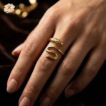 Close-up of a person wearing a gold-toned snake ring on their index finger. The ring features a bypass design with a textured, scale-patterned serpent head and a smooth, polished tail that curves around the finger by Zzilya fashion Jewellery