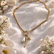 Gold necklace with star and pearl charm on a white fabric background with flowers by zzilya fashion