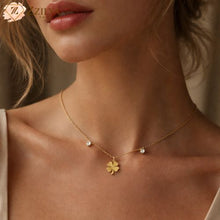 Gold necklace with a clover pendant worn by a model, brand 'Zzilya' visible.