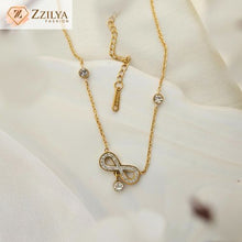 Gold necklace with a bow-shaped pendant on a white fabric background, featuring the brand 'Zzilya'.