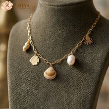 Necklace with shell and fish charms on a mannequin, branded 'ZZILYA'.