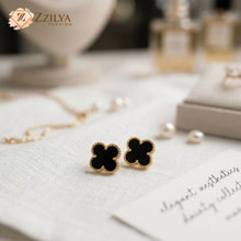 Black clover-shaped earrings on a white surface with 'ZZILYA' branding.