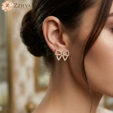 Close-up of a woman wearing bow-shaped earrings with 'ZZILYA FASHION' branding.