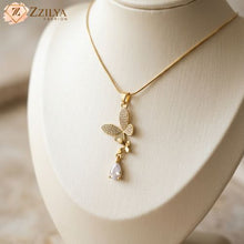 A Zzilya Fashion golden anti-tarnish necklace on a cream display stand, featuring a sparkling butterfly pendant with a hanging teardrop crystal; elegant 2026 minimalist jewelry trend.
