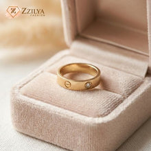 Gold ring with a diamond in a jewelry box, branded 'Zzilya'.
