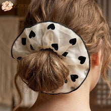White hair bun cover with black heart patterns on a person's hair.