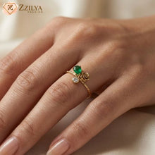 Dainty golden anti-tarnish ring by Zzilya Fashion featuring a pear-shaped green emerald stone, a clear round zircon, and a small gold rose detail on a textured gold band, worn on a model's hand.