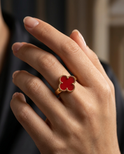 Hand wearing a red clover-shaped ring with a blurred background by Zzilya fashion Jewellery