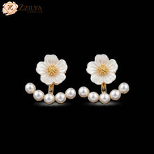 Flower-shaped earrings with pearl accents on a black background, branded 'ZZILYA'.