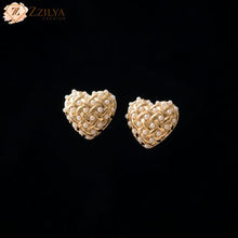 Heart-shaped gold earrings with pearl accents on a black background, branded 'ZZILYA'.