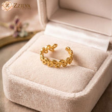 Gold leaf design ring on a pink cushion in a jewelry box with 'Zzilya' branding.