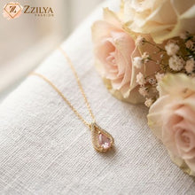Gold necklace with a pink pendant on a white fabric background with flowers by zzilya fashion