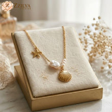 Gold necklace with star and shell pendant on a beige display box, branded 'Zzilya'.