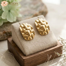 Gold statement earrings on a wooden stand with a soft background by zzilya Fashion