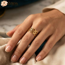 Gold floral link ring ring on a hand with a blurred background, featuring the brand 'ZZILYA'.