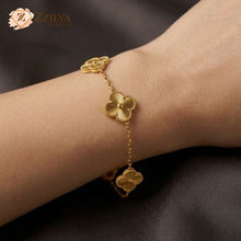 Gold bracelet with floral designs on a wrist against a dark background, featuring the brand 'ZZILYA'.