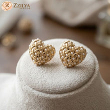 Gold earrings with pearl details on a white cushion, branded 'Zzilya Fashion'.