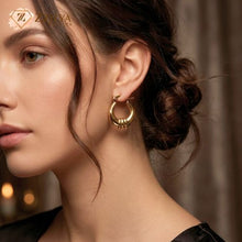 Close-up of a woman wearing gold hoop earrings by zzilya fashion