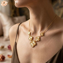 Gold clover necklace worn by a person with a blurred background by Zzilya fashion