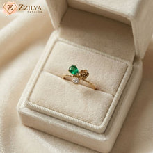 Gold ring with a green gemstone in a beige jewelry box, branded 'Zzilya'.