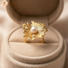 Gold ring with a pearl in the center on a beige jewelry display box by zzilya fashion