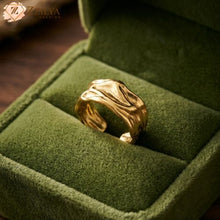 Golden statement ring on a green velvet cushion with 'Zzilya' branding.