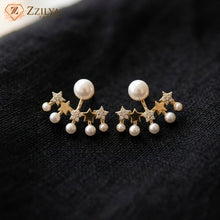 Close-up photograph of a pair of Korean-style star and pearl studded earrings for women from Zzilya Fashion, featuring gold-toned stars and multiple pearls on a black fabric background, available for under ₹99.