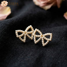 Minimalist Korean style double pearl bow stud earrings on a dark textured fabric background, Pinterest aesthetic jewelry by Zzilya Fashion under Rs 99.