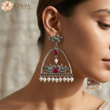 Close-up of a woman wearing an ornate earring with pearls and gemstones, branded 'Zzilya Fashion'.