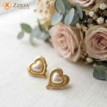 Heart-shaped gold earrings with a bouquet of flowers on a light background, featuring the brand 'Zzilya'.