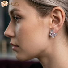 Close-up of a woman wearing butterfly-shaped earrings with 'ZZILYA' branding.